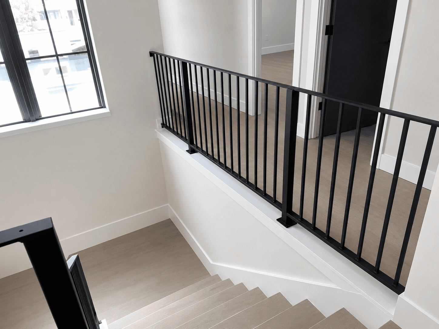Custom black metal railing on an interior stair landing overlooking the stairwell