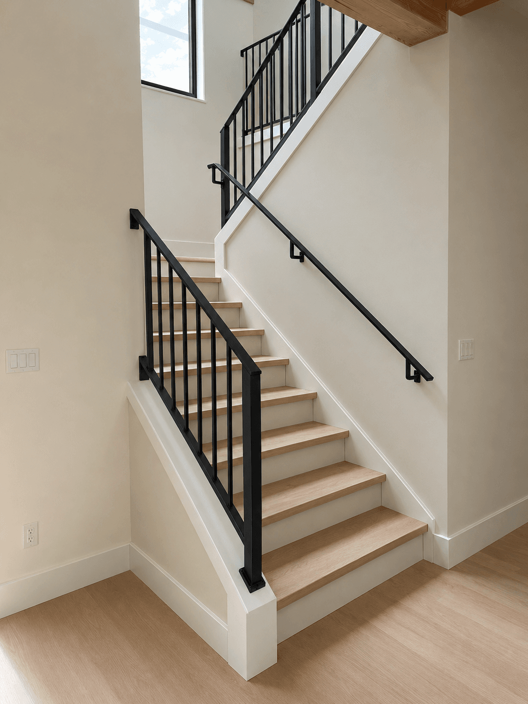 Custom black metal picket railing with a wall-mounted handrail on an interior staircase