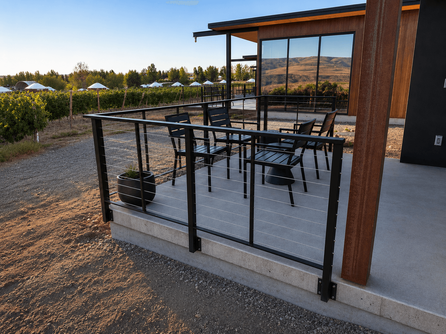 Black-framed horizontal cable railing around a concrete patio overlooking a vineyard